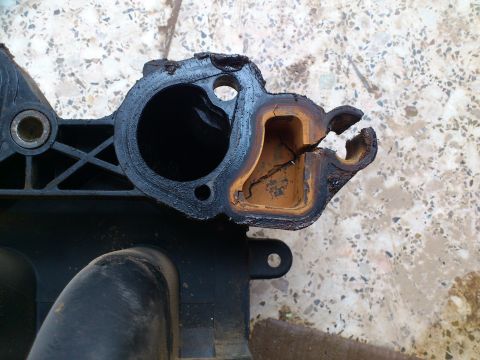 1998 Ford Crown Victoria - This is a close-up of a damaged plastic intake manifold part, showing significant wear and a large crack.