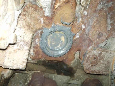 1998 Ford Crown Victoria - Close-up of a cylinder block heater plug, showing sealant applied to a rusty engine component.