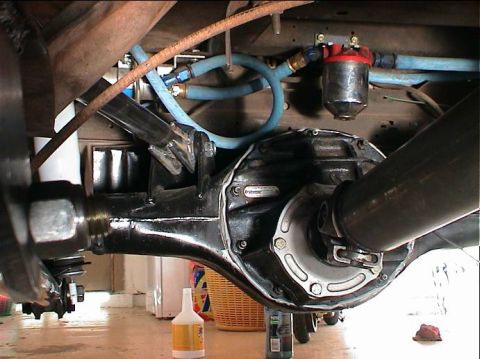 1979 Ford Bronco - Close-up view of a vehicle's rear axle, showing suspension components and a fuel filter with blue lines.