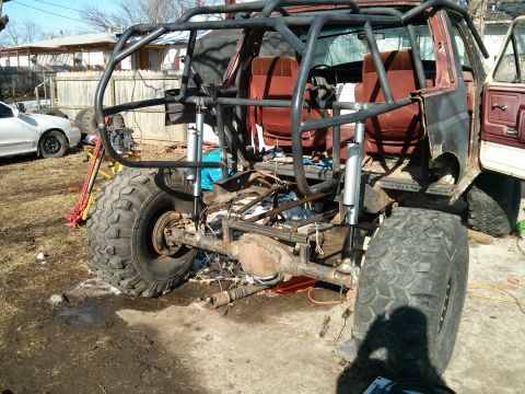 1986 Ford Bronco - This heavily modified off-road vehicle, likely a 1980s Ford Bronco, features a custom roll cage and oversized tires.