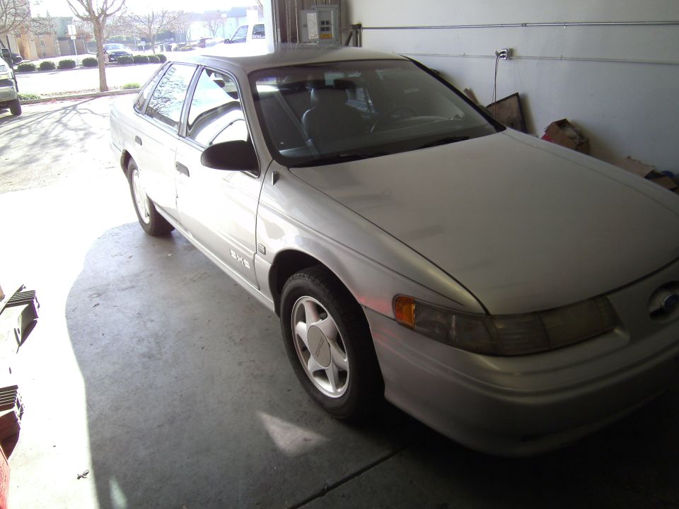 Silver 1992 Ford Taurus sedan parked in a garage, front 3/4 view