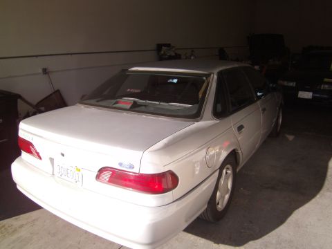 1992 Ford Taurus - Rear view of a white 1992 Ford Taurus sedan parked indoors.