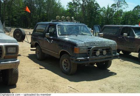 1993 Ford Bronco - A dark blue full-size Ford Bronco with a removable hardtop, roof-mounted four-lamp light bar, tubular front brush guard with driving lights…