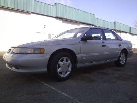 1992 Ford Taurus - Silver 1992 Ford Taurus sedan parked in front of a building with large garage doors.