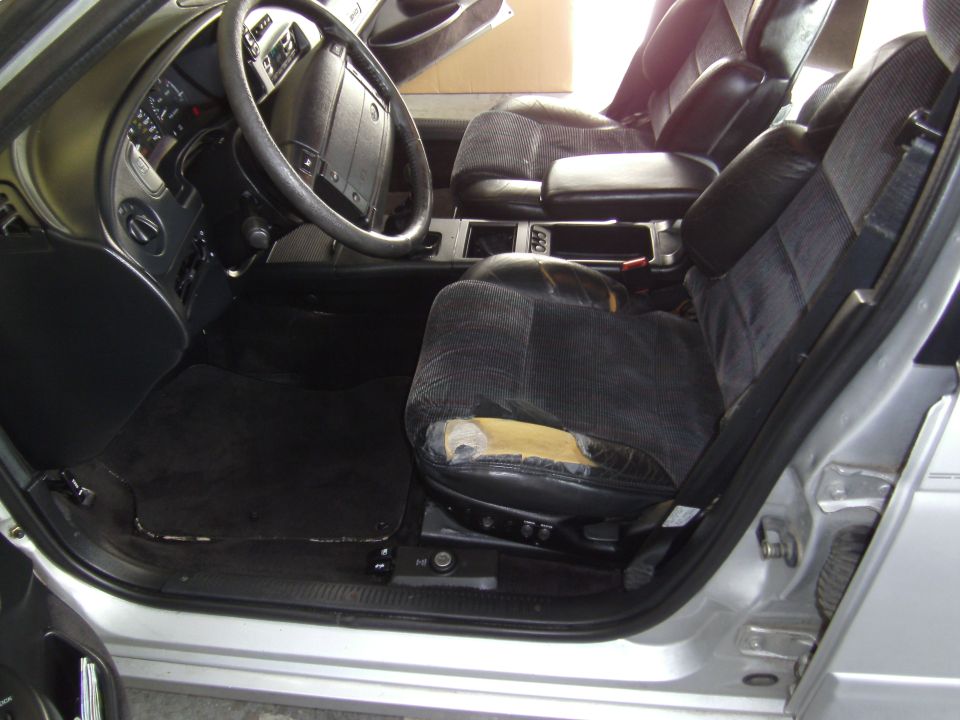 Silver car interior with torn driver's seat, black dashboard, and steering wheel