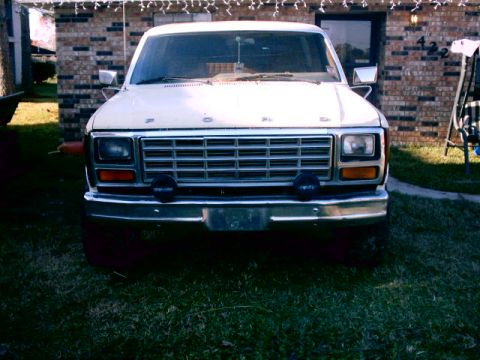 1980 Ford Bronco - This truck's front end features a prominent grille and bumper, with a house in the background.