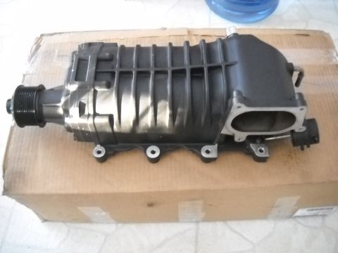 1954 Ford F-100 - A black supercharger with a ribbed pulley is shown resting on a cardboard box.