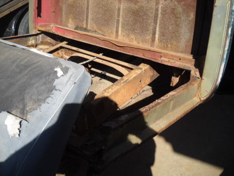 1954 Ford F-100 - The interior of a truck bed shows a worn seat and significant rust on the frame and bed floor.