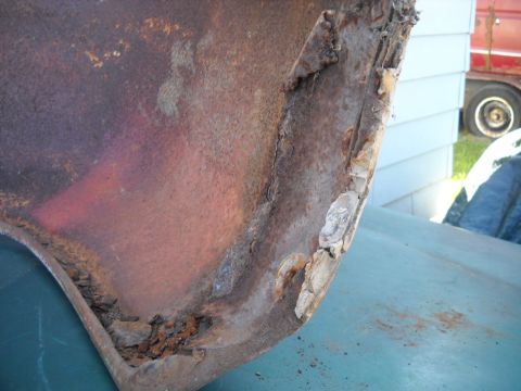 1954 Ford F-100 - Detail of heavily corroded metal, likely from a vehicle part. The edge shows significant rust and damage.