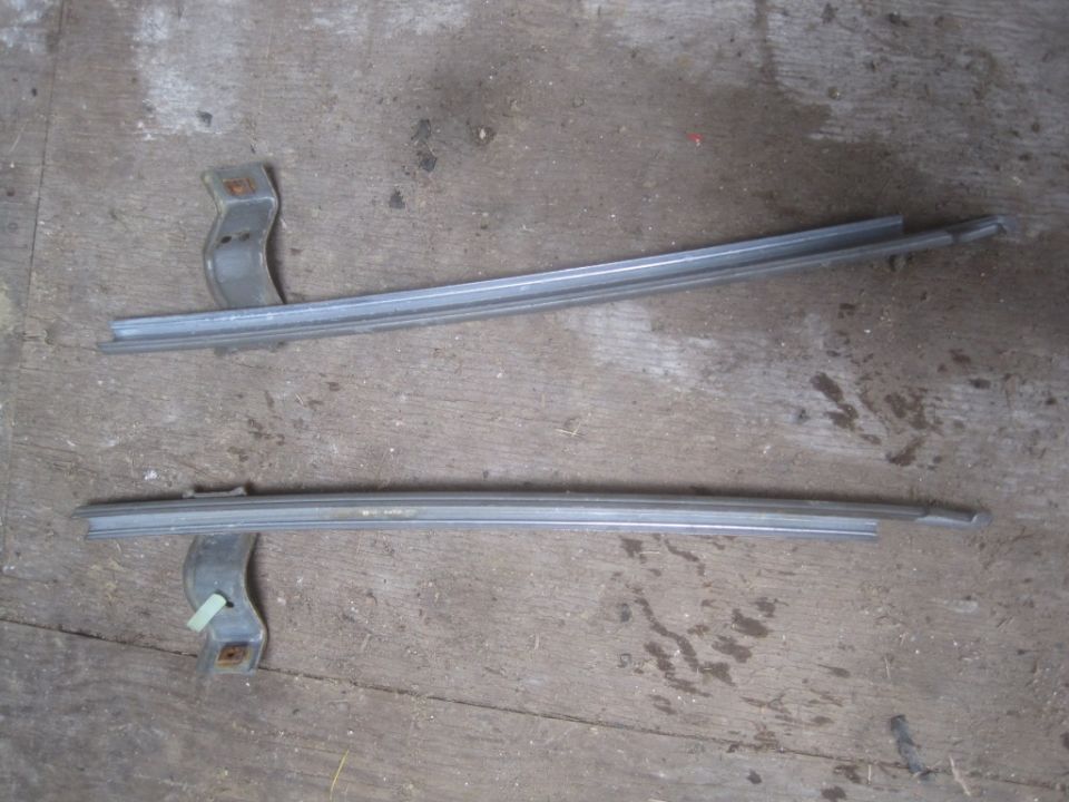 Two metal window trim pieces with mounting brackets on a wooden surface