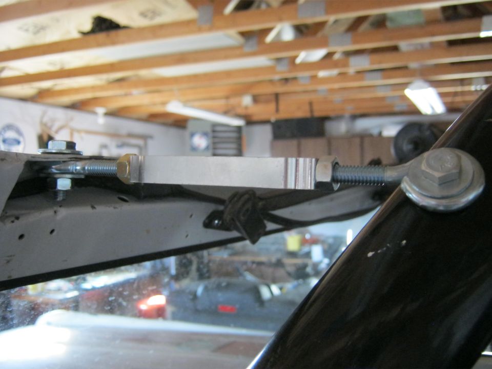 Turnbuckle assembly attached to a vehicle's windshield frame, with a black A-pillar visible