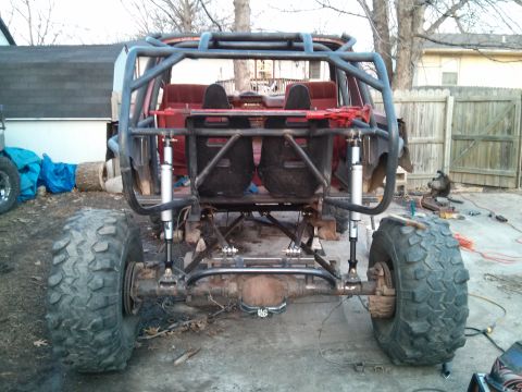 1986 Ford Bronco - This heavily modified off-road vehicle features a custom roll cage and suspension system, obscuring its original make and model.