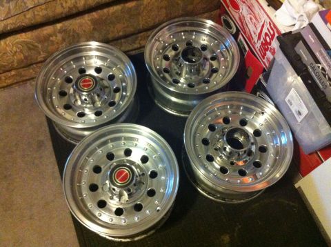 1992 Ford F-150 - Set of four aluminum wheels with red center caps are displayed on a dark surface.