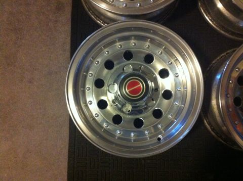 1992 Ford F-150 - Several chrome truck wheels are shown, with one in the foreground a red and silver center cap.