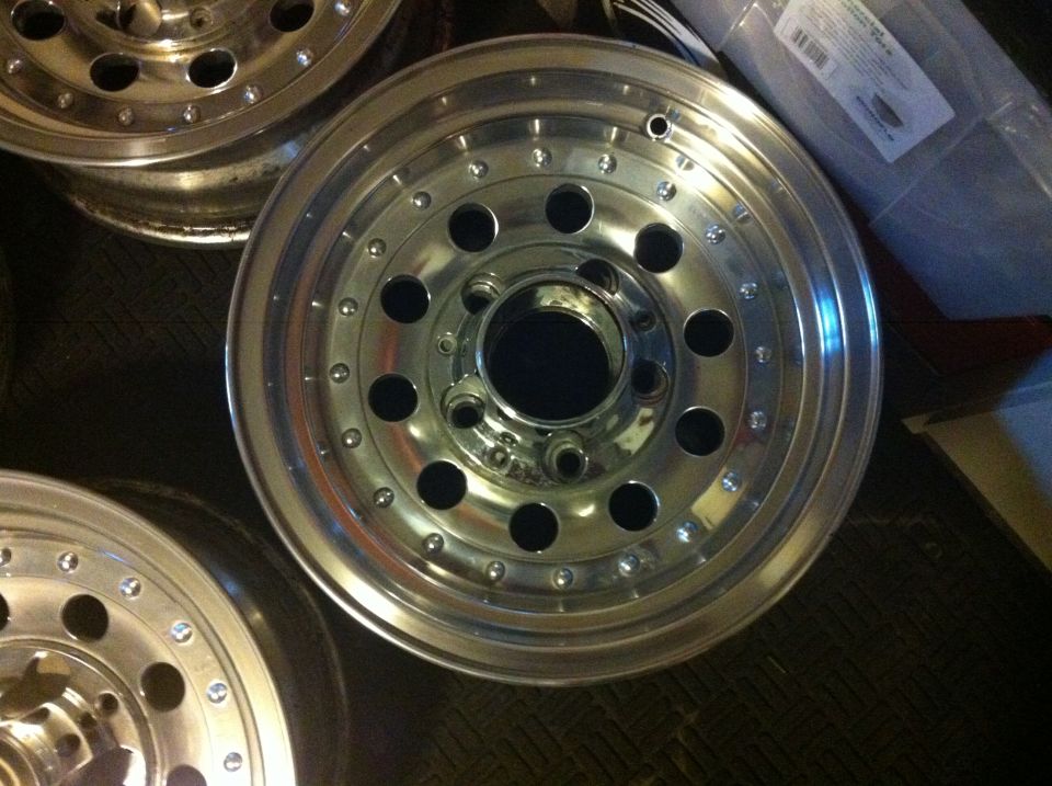 Three polished aluminum alloy wheels with multiple lug holes and a center cap opening