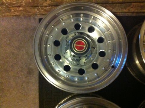1992 Ford F-150 - A single chrome wheel with a red and gold center cap is shown, with another wheel partially visible to the right.