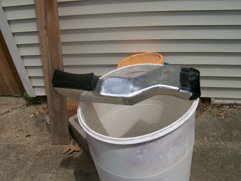 1990 Ford F-150 - A chrome air intake duct, likely for an engine, is shown resting on a large white bucket outdoors.