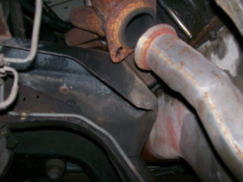 1990 Ford F-150 - Close-up view of the exhaust manifold and pipe connection, showing a red marking on the pipe.