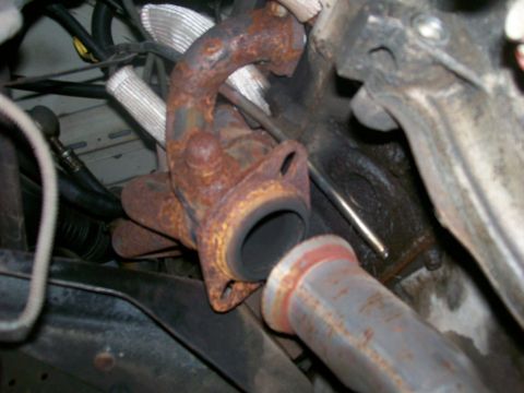 1990 Ford F-150 - Close-up of a rusted exhaust manifold and pipe assembly, likely from an older vehicle.