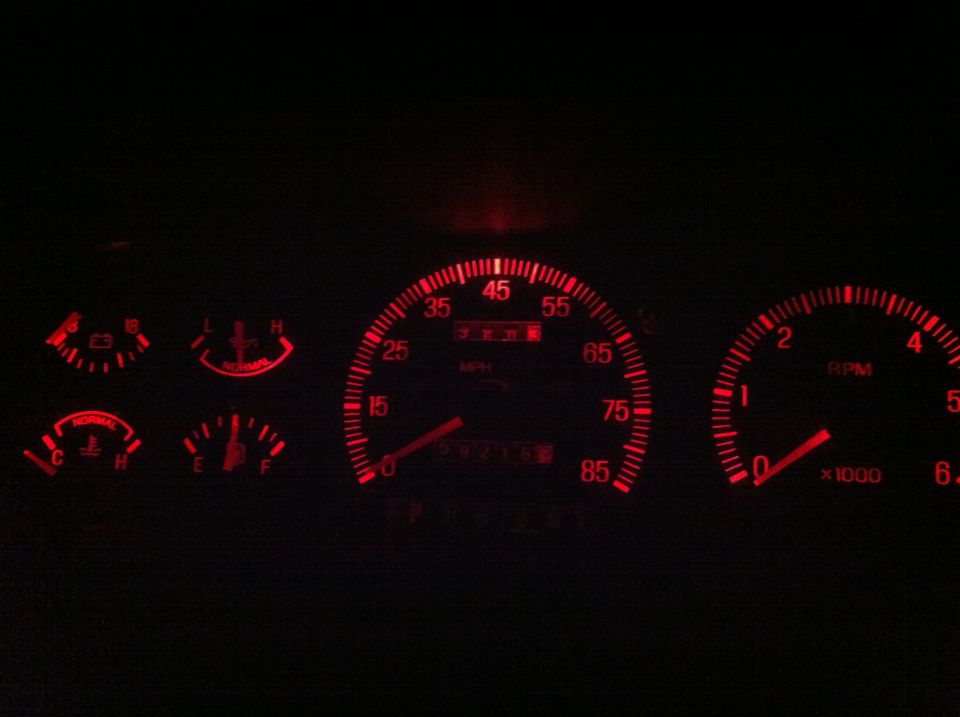Red-lit instrument cluster at night showing 85 mph speedometer, tachometer, and fuel, temp, oil, battery gauges