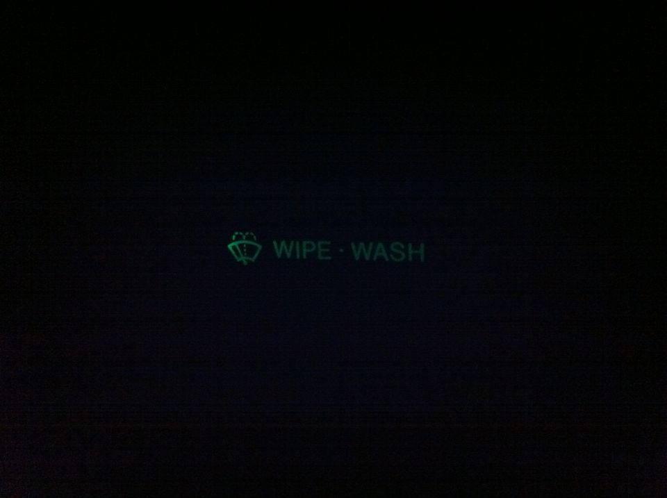 Green backlit 'WIPE WASH' wiper switch label glowing in a dark truck interior
