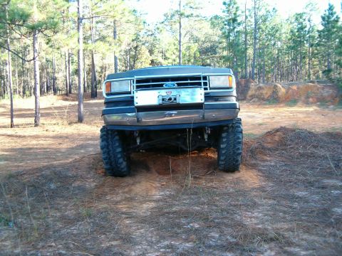 1991 Ford Bronco - This lifted 1990s Ford Bronco is shown from the front, equipped with oversized tires for off-road use.