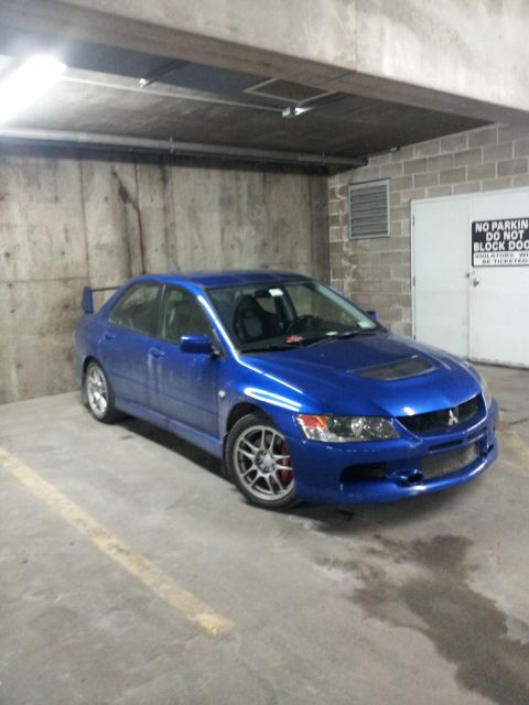 2006 Mitsubishi Evolution - A blue Mitsubishi Lancer Evolution VIII is parked in a concrete garage with a 'No Parking' sign on the door.