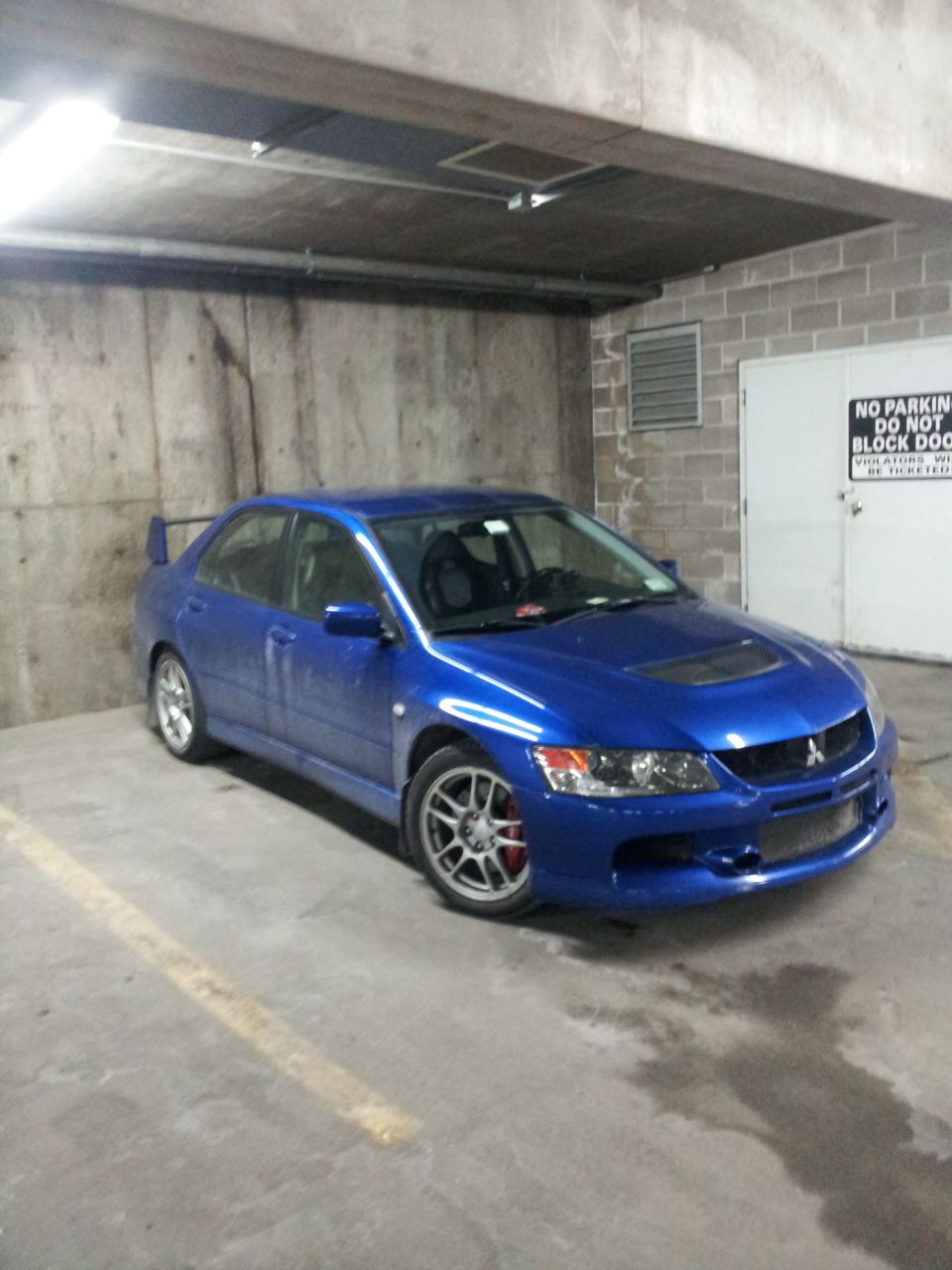 Blue Mitsubishi Lancer Evolution VIII parked in a garage. Has a rear spoiler and red brake calipers