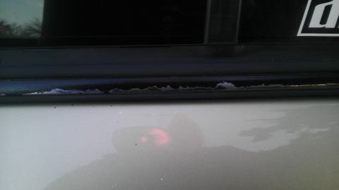 2000 Mercury Grand Marquis - Close-up of peeling paint on the door frame of a silver vehicle, revealing damage to the trim.