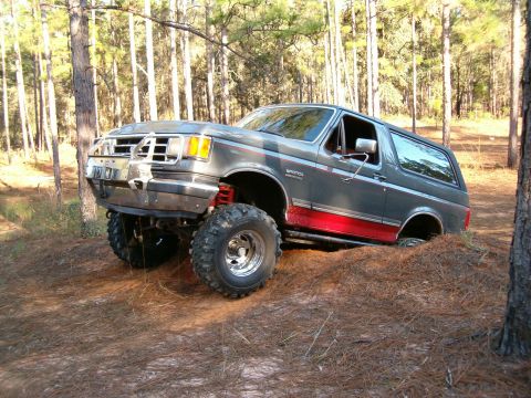 1991 Ford Bronco - This 1991 Ford Bronco is shown navigating a challenging off-road trail in a forest setting.