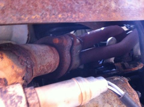 1990 Ford F-150 - The rusted exhaust system components are visible under the vehicle, with a SuperMotors logo in the corner.