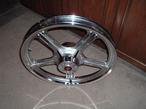 2002 Harley-Davidson Sportster Custom - A single chrome motorcycle wheel is shown against a wooden cabinet background.