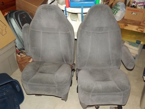 1981 Ford Bronco - Two grey fabric car seats with armrests are shown from the front in a cluttered storage space.