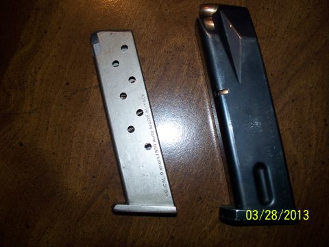 2000 Nissan Xterra - Two firearm magazines are shown, one made of silver metal and the other black, resting on a wooden table.