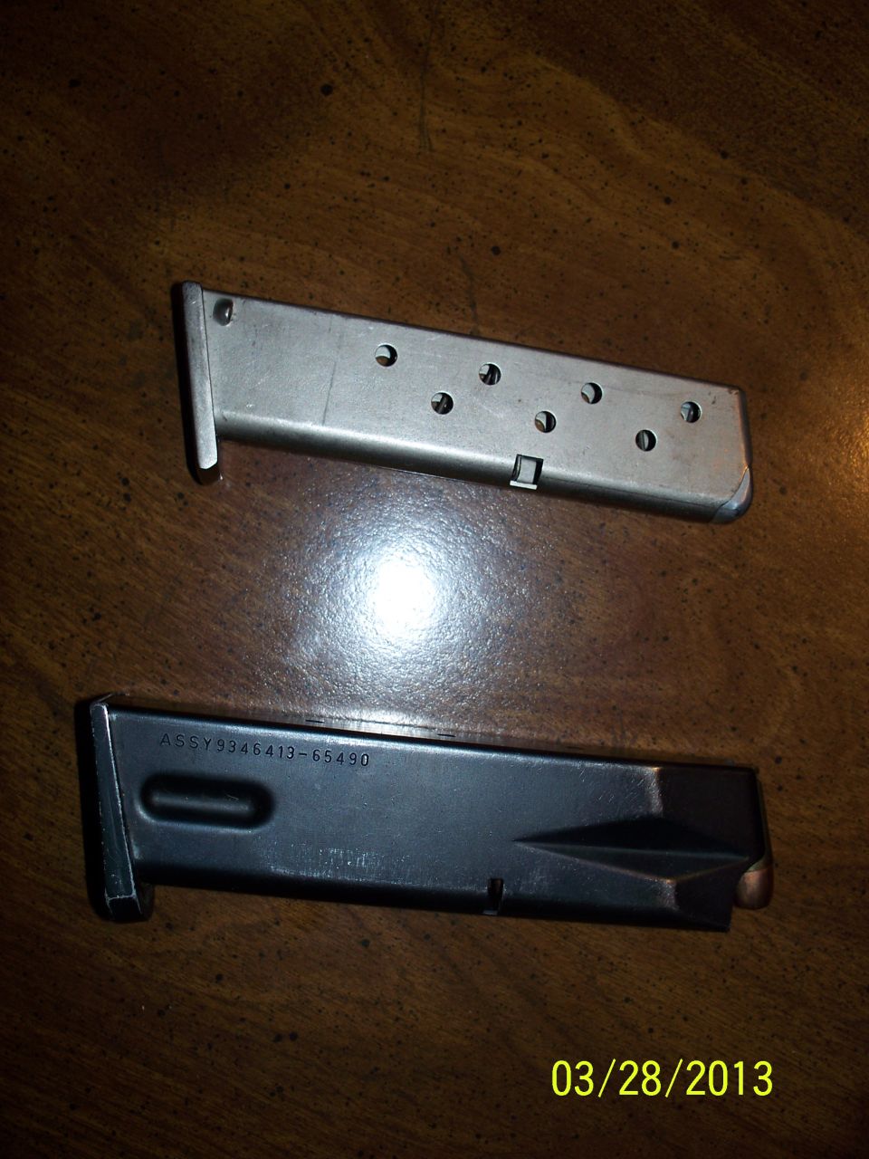 Stainless witness-hole pistol magazine above a blued double-stack magazine marked ASSY 9346413