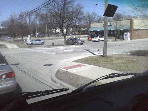 2003 Ford Crown Victoria - Several vehicles are visible at a street intersection with a 7-Eleven store in the background.