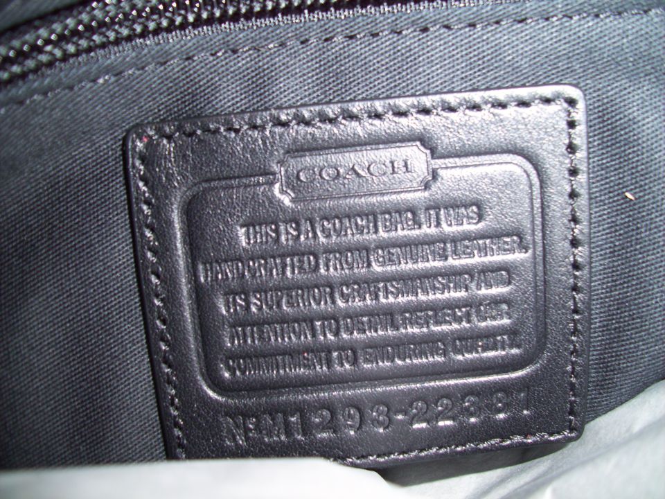 Close-up of a black leather Coach bag label with embossed text and a serial number