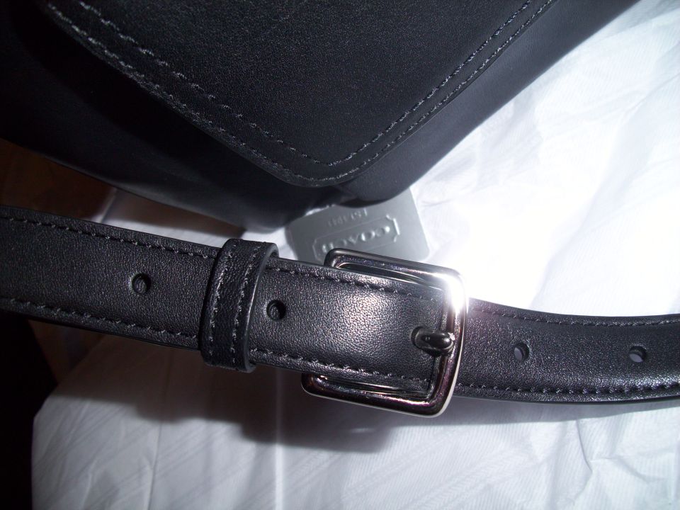 Black leather bag strap with silver buckle and Coach tag
