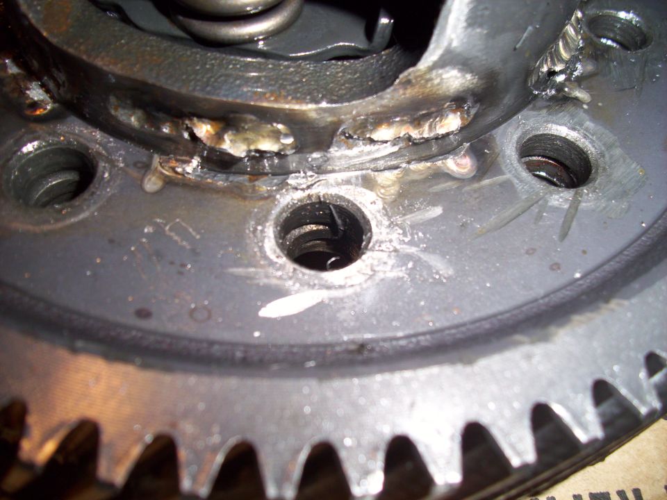 Close-up of a metal gear with visible welding and a spring mechanism inside