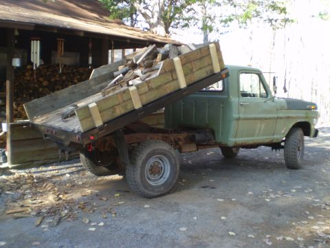 1979 Ford Bronco - This dump truck, likely from 1979, is seen from the side, carrying a load of firewood.