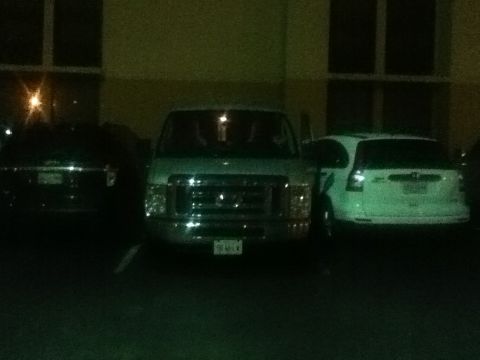 2006 Ford E350 - Three vehicles parked in a lot at night. The van in the center is the most prominent subject.