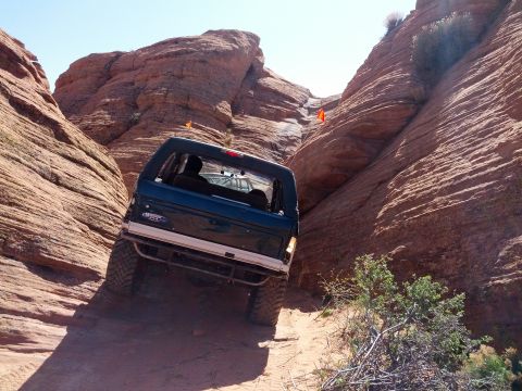1994 Ford Bronco - Ford Bronco navigates a challenging off-road path through a desert canyon.