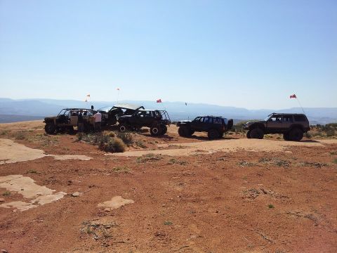 1994 Ford Bronco - Several modified off-road vehicles are parked on a rocky, arid landscape under a clear blue sky.