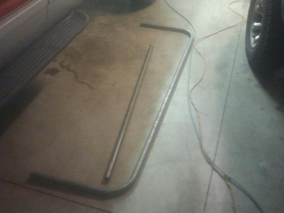 Curved metal trim piece lying on concrete floor next to a ribbed mat