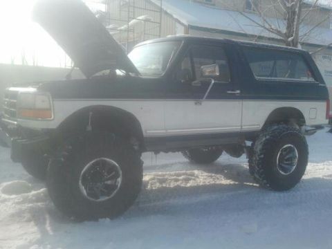 1994 Ford Bronco - This lifted Ford Bronco is parked in the snow with its hood up.