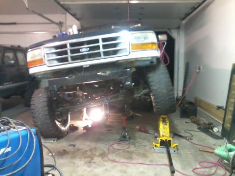 1994 Ford Bronco - Front end of a 1992 Ford Bronco being worked on in a garage. Another vehicle is parked to the left.