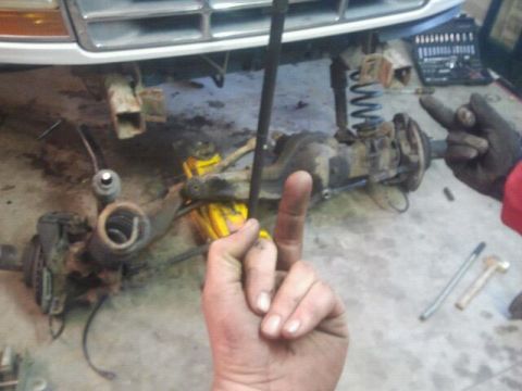1994 Ford Bronco - Mechanic's hand gestures while working on vehicle suspension components in a garage.