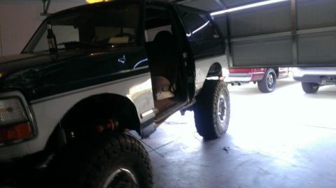 1994 Ford Bronco - A modified Ford Bronco sits in a garage with its door open, alongside other vehicles.