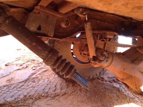 1994 Ford Bronco - A close-up view of the undercarriage reveals the driveshaft, leaf springs, and suspension system of an off-road vehicle.