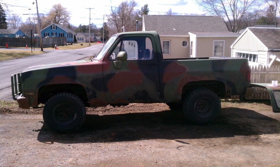 Side view of a camouflage pickup truck with a brush guard